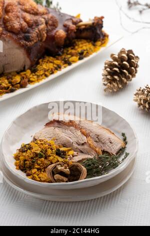 Gebratener Schweineschulterschinken mit Nüssen auf einem weißen Gericht und Speisen auf dem Hintergrund Stockfoto