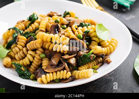 Fusilli Pasta mit Spinat und Pilzen auf einem weißen Teller. Vegetarische / vegane Speisen. Italienische Küche. Stockfoto