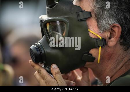 Artikeldetails mit einem Mann, der eine alte, alte, alte, militärische Gasmaske auf sein Gesicht legt. Stockfoto