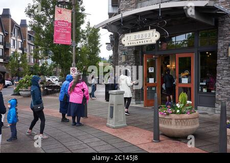 Maskierte Kunden stehen am 13. Juni 2020 während der COVID-19-Pandemie in Lake Oswego, Oregon, an und üben soziale Distanzierung außerhalb einer Bäckerei und eines Cafés. Stockfoto