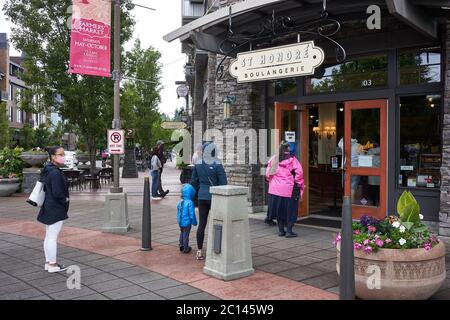 Maskierte Kunden stehen am 13. Juni 2020 während der COVID-19-Pandemie in Lake Oswego, Oregon, an und üben soziale Distanzierung außerhalb einer Bäckerei und eines Cafés. Stockfoto