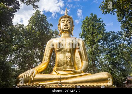 Phayao, Thailand - 24. Nov 2019: Goldene Buddha Statue auf grünem Baum und blauem Himmel Hintergrund mit natürlichem Licht Stockfoto