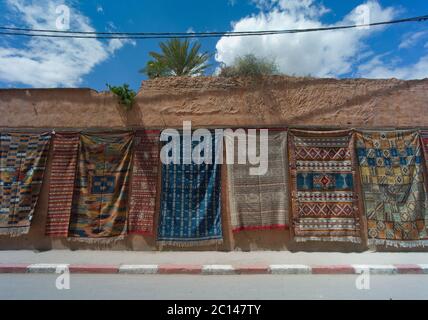 Teppiche zum Verkauf hängen an einer Wand entlang der Straße in der Nähe von Fes in Marokko Stockfoto