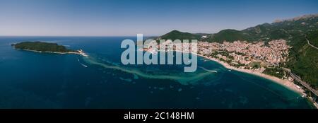 Panorama von der Drohne. Die Küste von Budva in Montenegro und die Insel St. Nikolaus. Die Landenge zwischen der Insel und der Stadt. Grüne Quelle Stockfoto