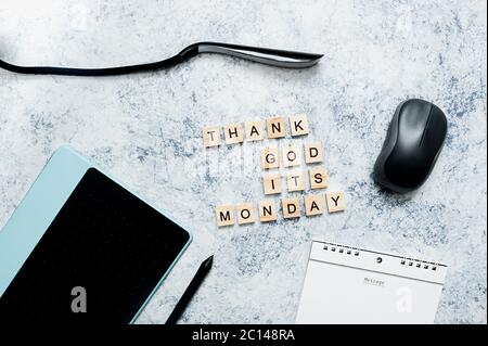 Postkarte für den Bürourlaub Gott sei Dank für Montag. Grafiktablett, Stylus, Maus, Notizblock auf einer Spirale und eine elegante dünne USB-Lampe auf einem blauen Zement Stockfoto