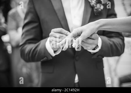 Der Bräutigam trägt einen Ring für die Braut. schwarz / weiß Foto Stockfoto