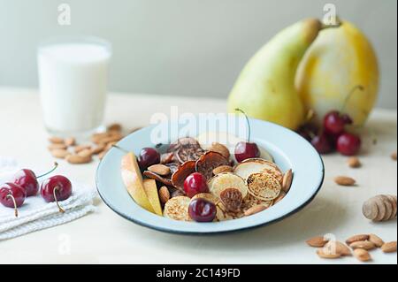 Kleine Pfannkuchen mit Birnen, Kirschen, Nüsse in Metallplatte vor dem Hintergrund der Küchentisch mit Obst und Milch. Trending Lebensmittel Müsli Pfannkuchen. br Stockfoto