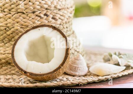 Stillleben mit Strohhut, halb Kokosnuss und Muscheln. Nahaufnahme. Stockfoto