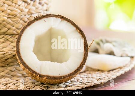 Stillleben mit Strohhut, halb Kokosnuss und Muscheln. Nahaufnahme. Stockfoto