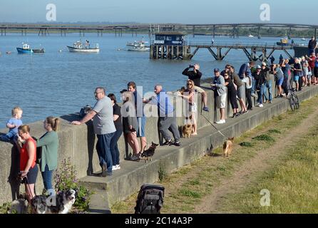 Die Menschen säumen die Meeresmauer, um zu beobachten, wie HMM Algeciras, das größte Containerschiff der Welt, Canvey Island passiert, während sie gegen Ende ihrer Jungfernfahrt nach Großbritannien zum DP World London Gateway Hafen in Tilbury, Essex, auffährt. Stockfoto