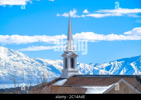 Das Dach der Kirche mit einem modernen Turmdesign gegen verschneite Berge und See Stockfoto