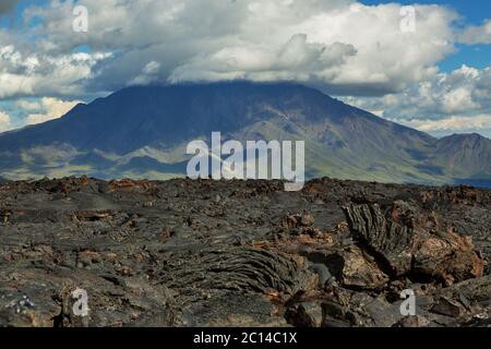 Lavafeld am Vulkan Tolbachik, nach Ausbruch im Jahr 2012 auf Hintergrund groß beim Vulkan, Kamtschatka Stockfoto