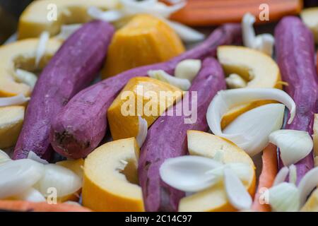 Bunte Mischung aus Wurzelgemüse: Karotten, gelber Kürbis, lila Süßkartoffeln, Zwiebeln und Knoblauch. Stockfoto