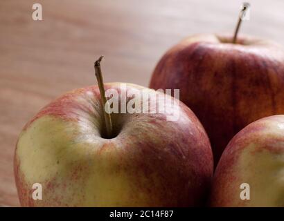 Drei Äpfel mit Stahl liegen auf einem verwischten Holztisch gegeneinander Stockfoto