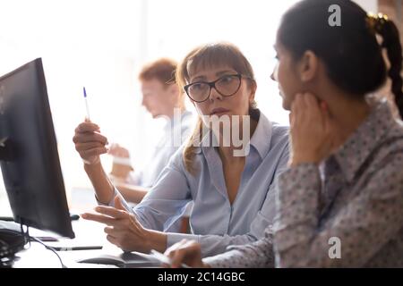 Serious businesswoman Mentor Lehre neue Mitarbeiter, mit Computer Stockfoto