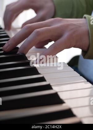 Nahaufnahme der Hände eines Pianisten, die auf einem Klavier mit weißen und schwarzen Tasten spielen. Vertikales Bild Stockfoto