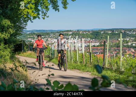 Großmutter und Enkelin reiten auf ihren Mountainbikes und haben Spaß an einem sonnigen Nachmittag in den Weinbergen über der Stadt Stuttgart, Stockfoto