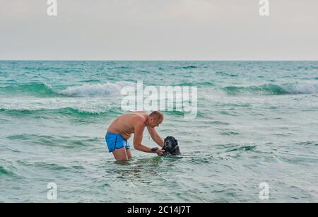 Ein Mann mit Hund, der im Meer schwimmend ist Stockfoto