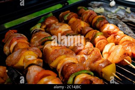 Köstliche gegrillte Gemüse- und Fleischspieße in einer Kräutermarinade auf dem Grill, draußen. Leckere Speisen auf Spieße braten Stockfoto