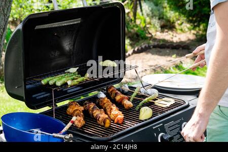 Frischer, zartgrüner Spargel, mit Gemüse- und Fleischspiessen in einer Kräutermarinade auf dem Grill gekocht, draußen. Leckeres Essen. Sommer Picknick im Garten Stockfoto