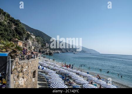 Urlaub Strand mit bunten Regenbogen Liegestühlen und Sonnenschirmen. Resort Strand. Monterosso al Mare, Cinque Terre, Italien Stockfoto