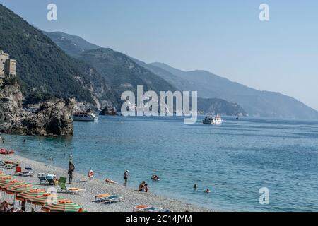 Urlaub Strand mit bunten Regenbogen Liegestühlen und Sonnenschirmen. Resort Strand. Monterosso al Mare, Cinque Terre, Italien Stockfoto