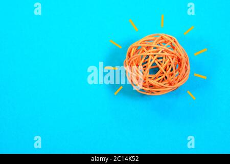 Konzept von Ideen und Innovation. Glühbirne Konzept der orange Saite Ball leuchtet auf blauem Hintergrund Stockfoto