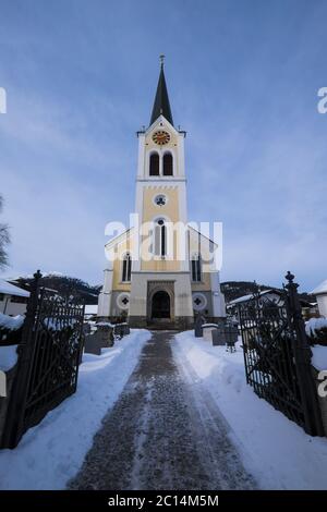 Römisch-katholische Pfarrkirche in Riezlern, Vorarlberg in Österreich im Winter Landschaft mit Schnee und Zaun Stockfoto