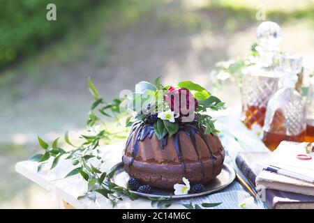 Schokoladenkuchen mit Blumen und drei Whiskey-Dekantern Stockfoto