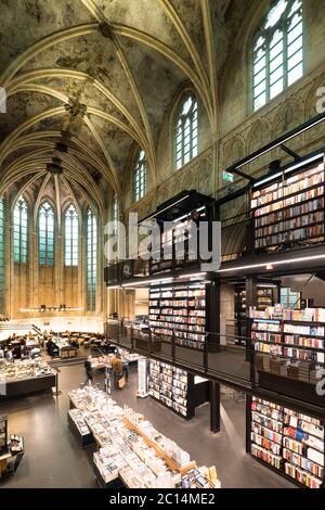 Innenansicht der Dominikanerkirche, die in eine Buchhandlung mit Restaurant, Kunden, Decken und Säulen der Kirche in Maastricht, Niederlande, umgewandelt wurde Stockfoto