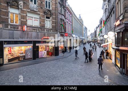 Blick auf die Grote Straat in Maastricht, Niederlande, mit beleuchteten Geschäften und Einkaufsbummel am Ende des Nachmittags Stockfoto