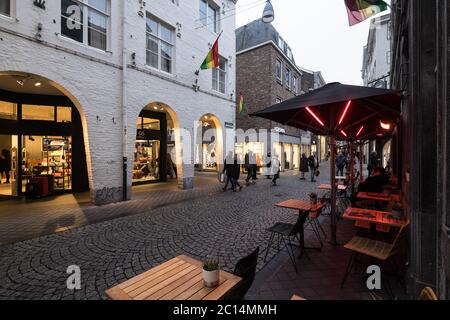 Geschäfte und Café mit beleuchteten Schaufenstern am Kersenmarkt am Ende des Winternachmittages in Maastricht, Niederlande Stockfoto