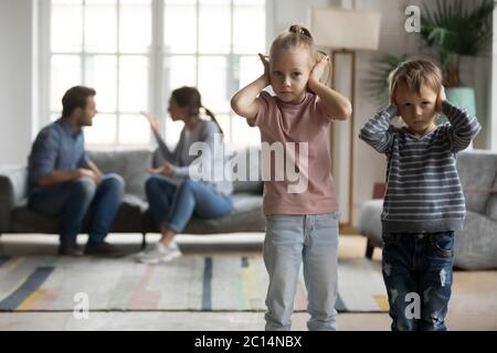 Unglückliche kleine Kinder, die Ohren bedecken, leiden an Elternargumenten Stockfoto