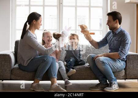 Glückliche Mutter und Vater spielen Puppentheater mit entzückenden Kindern Stockfoto