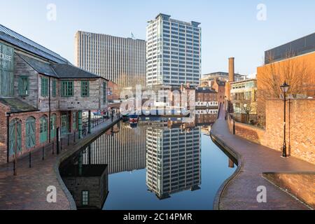 Birmingham, UK - 24/02/19: Gas Street Kanalbecken mit festgeschobten Schmalbooten. Alte Kanalgebäude und moderne Turmblöcke spiegeln sich im Wasser. Stockfoto