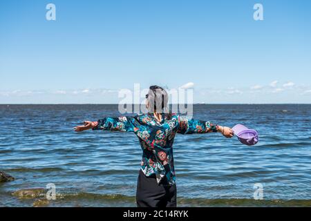 Ein Chinese, der den Wind und die Meeresküste der Ostsee in Peterhof genießt Stockfoto