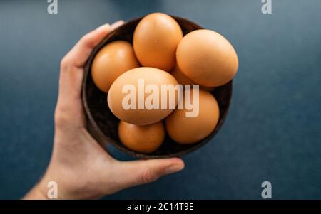 Person, die die besten Eier aus Schüssel rohe Hühnereier auf dem hölzernen Hintergrund. Leerzeichen für Text Stockfoto