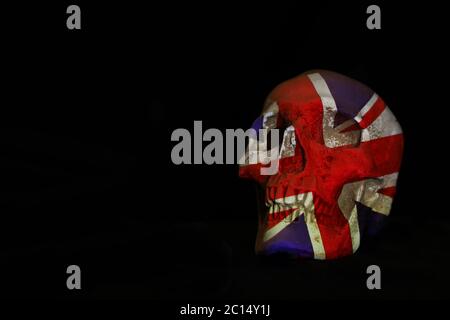 Ein isolierter weißer Schädel, der auf einem schlichten schwarzen Hintergrund mit der Union Jack oder britischen Flagge über ihn projiziert wird. Stockfoto