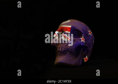 Neuseeland Nationalflagge drapiert oder projiziert über einen weißen Schädel isoliert gegen einen schlichten schwarzen Backgorund. Stockfoto