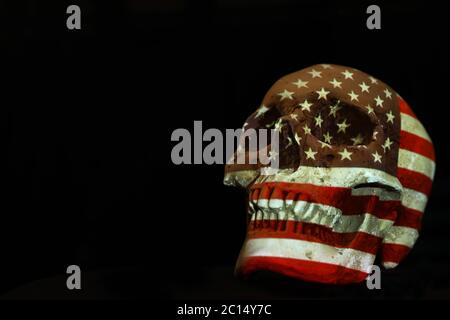 Isolierter weißer Schädel mit der amerikanischen Flagge der Vereinigten Staaten von Amerika, die darüber projiziert wird. Schlichter schwarzer Hintergrund. Covid-19 Corona-Virus oder Pistole Kontrolle Stockfoto