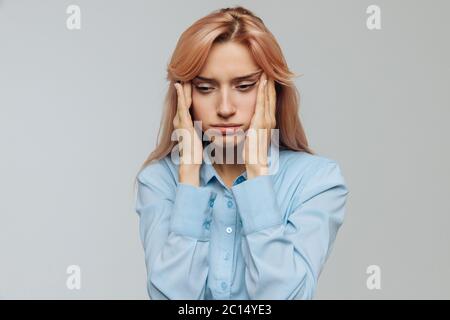 Müde junge Frau in blauem Hemd will bei der Arbeit oder Universität schlafen, ihre Augen mit den Fingern öffnen, zucken, um nicht einzuschlafen. Fehlende e Stockfoto