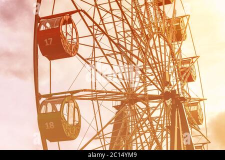 Riesenrad mit bunten Kabinen gegen den Himmel mit Wolken und Sonnenstrahlen im Park an einem sonnigen Frühlingstag. Stockfoto