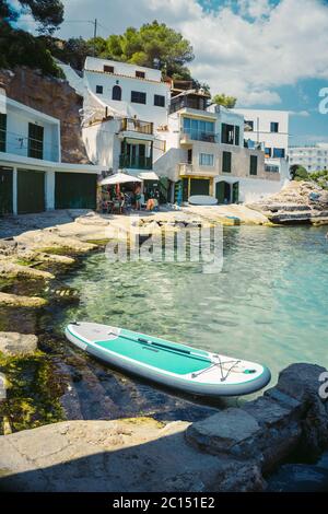 Panoramablick auf die mediterrane Küste mit einigen weißen Villen an der Küste, Felsen und blauem Himmel mit weißen Wolken. Mallorca. Balearen. Stockfoto
