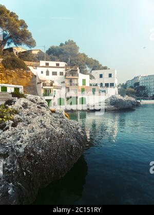 Panoramablick auf die mediterrane Küste mit einigen weißen Villen an der Küste, Felsen und blauem Himmel mit weißen Wolken. Mallorca. Balearen. Stockfoto