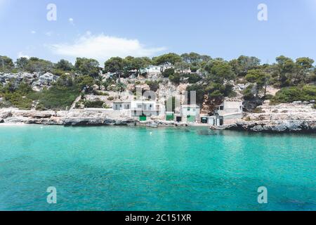 Panoramablick auf die mediterrane Küste mit einigen weißen Villen an der Küste, Felsen und blauem Himmel mit weißen Wolken. Mallorca. Balearen. Stockfoto