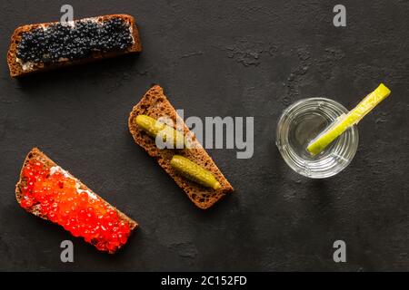 Glas Wodka mit Limette und verschiedene Sandwiches mit Kaviar und Gurken Stockfoto