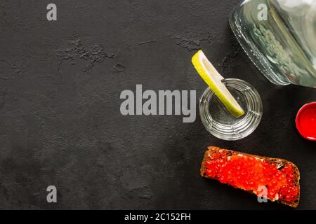 Wodka, Roggenbrot mit rotem Kaviar auf schwarzem Hintergrund mit Platz für Text Stockfoto