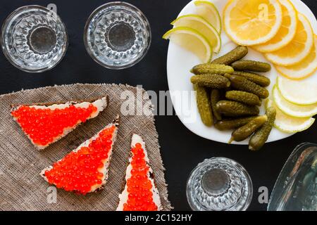 Teller mit Gurken, Zitrone und Limette, Sandwiches mit rotem Kaviar und Wodka Stockfoto
