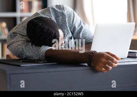 Überarbeiteter afrikanischer Angestellter schläft am Arbeitsplatz Schreibtisch Stockfoto
