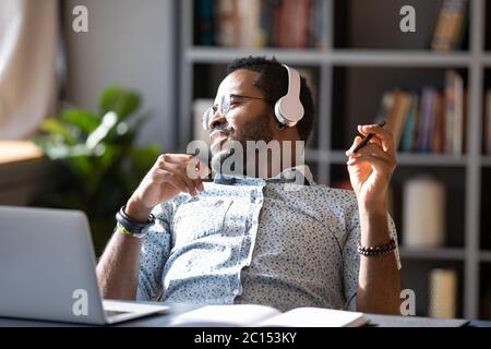 Afrikanischer Kerl tragen Kopfhörer Musik hören genießen Pause am Arbeitsplatz Stockfoto